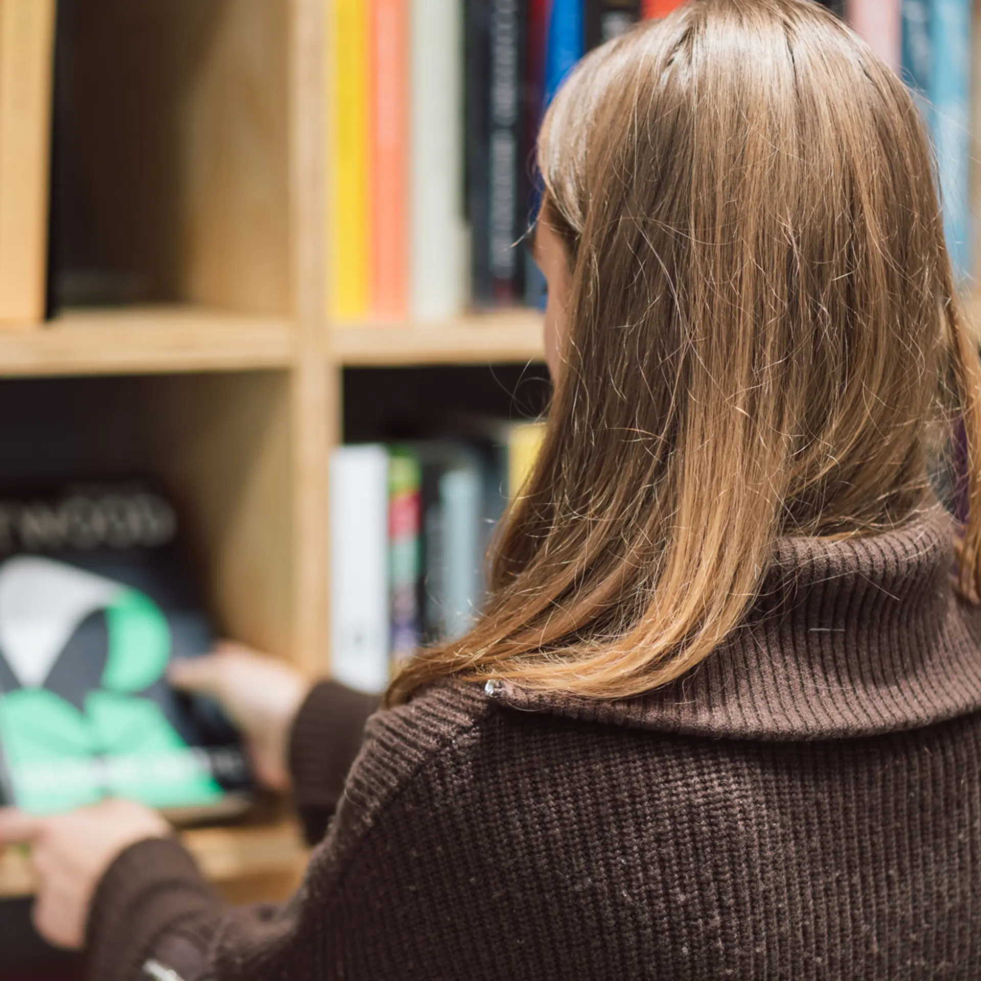 Jente ser på en bok i et bibliotek