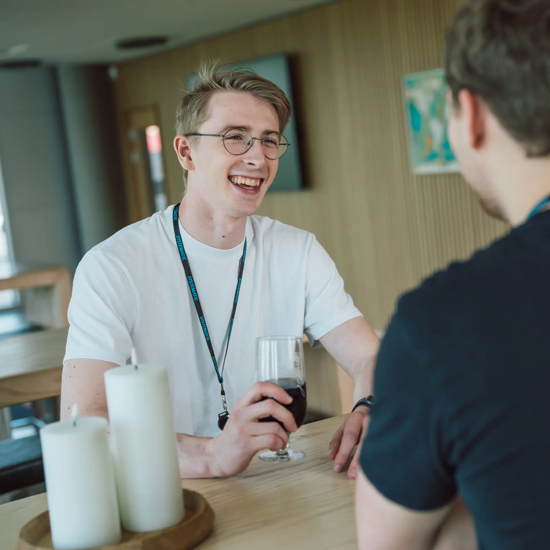 Two Systematic employees enjoying a casual conversation at the Friday Bar, with one holding a drink and smiling in a relaxed, informal setting.